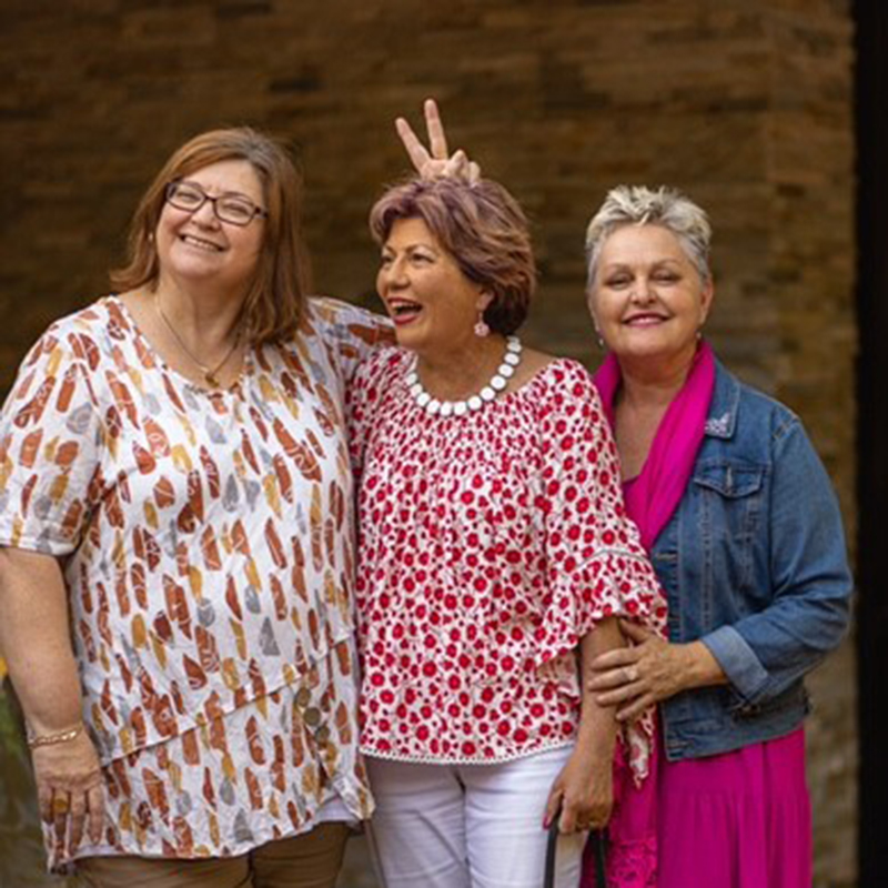 Colleen standing between Sharon (aka Hon) and Deb. Hon is holding up two fingers behind Colleen‘s head with a mischievous smile on her face. Colleen standing between Sharon (aka Hon) and Deb. Hon is holding up two fingers behind Colleen‘s head with a mischievous smile on her face.